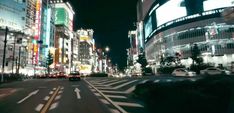 a city street filled with lots of traffic and tall buildings lit up in the night