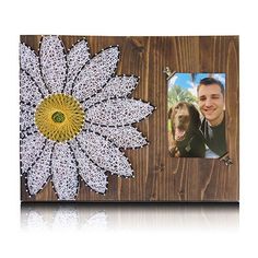 a wooden frame with a white and yellow flower on the front, and a photo of a man's face in the middle