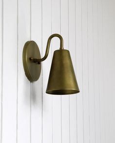 an old fashioned brass wall light with a bell on it's arm against a white painted wall