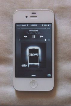 an iphone is sitting on a bed with the screen turned off and music player running