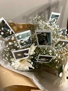 a bouquet of white flowers and pictures on a table