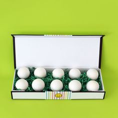 six white golf balls in a box on a green background