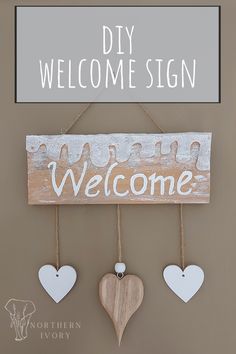 a wooden welcome sign hanging on a wall with hearts attached to it and the words, diy welcome sign