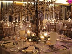 a table set up for a formal dinner with candles and centerpieces in the center