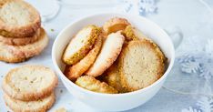 a white bowl filled with cookies next to some cut in half ones on top of a table