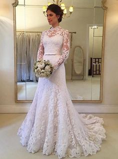 a woman standing in front of a mirror wearing a white wedding dress and holding a bouquet