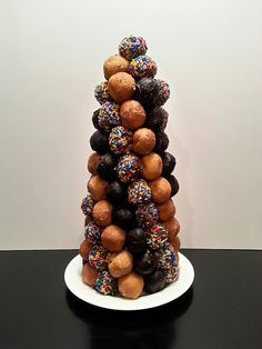 a tower of donuts with sprinkles on top sits on a black table