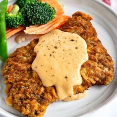 a white plate topped with meat patties covered in gravy and broccoli