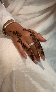 a woman's hand with henna tattoos on her left arm and the bride's wedding ring