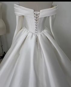 the back of a white wedding dress on a mannequin headdress stand