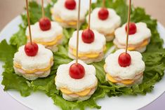 small appetizers are arranged on top of lettuce with cherries and cheese