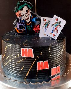 a birthday cake decorated with playing cards and joker on the top, sitting on a silver platter