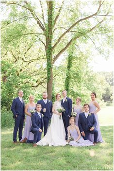 a bride and groom with their bridal party in front of a large oak tree