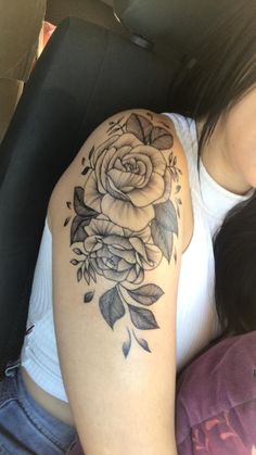 a woman with a flower tattoo on her arm sitting in the back seat of a car