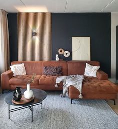 a living room with a brown couch and coffee table in front of a blue wall