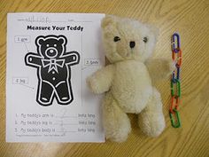 a teddy bear sitting on top of a piece of paper next to a pair of scissors