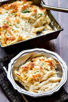 two pans filled with macaroni and cheese on top of a wooden table