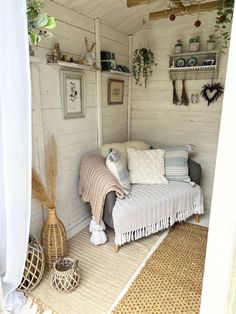 a couch sitting in the corner of a room next to a shelf filled with potted plants