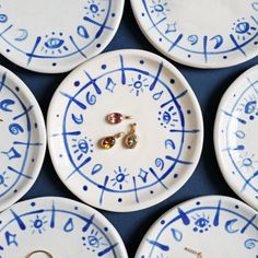 several white and blue plates with zodiac signs on them, one has two gold earrings