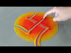 a person is using a sponge to decorate a logo on a surface with orange and yellow colors