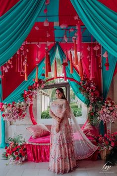 a woman standing in front of a bed covered in pink and blue draping