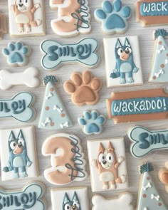 decorated cookies are arranged in the shape of dogs and paw - shaped letters on a table