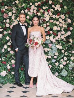 a bride and groom standing in front of a floral wall