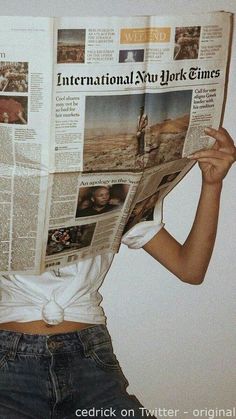 a woman reading a news paper with her hands on her hips