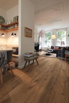 a living room with hard wood flooring and furniture in the corner, next to a dining table