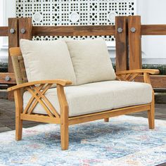 a wooden chair sitting on top of a rug next to a bench with two pillows