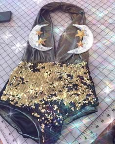 a bathing suit with gold sequins and crescent moon on the back, sitting on a ruler