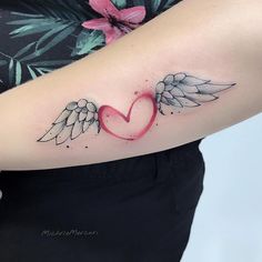 an angel wing and heart tattoo on the arm