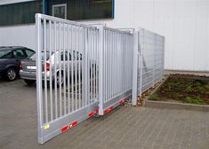 a car is parked in front of a metal gate that has been locked to the side