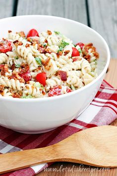 pasta salad in a white bowl on a red and white checkered tablecloth