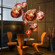 a modern dining room with orange chairs and hanging lights above the table, on which is a round glass chandelier