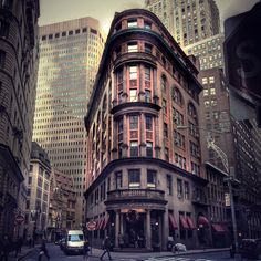 a city street with tall buildings and people walking on the sidewalk in front of it