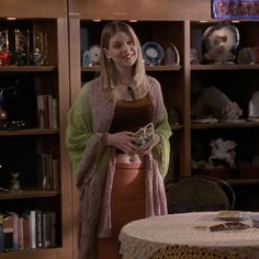 a woman standing next to a table holding a book