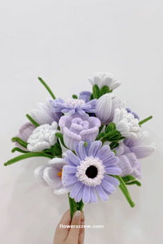 a person holding a bouquet of flowers with purple and white flowers in the center, on a white background