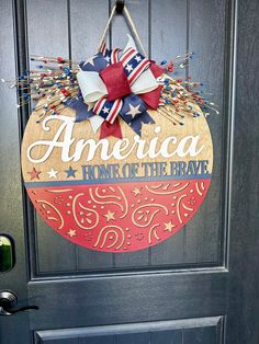 an american home of the brave door hanger on a front door with red, white and blue decorations