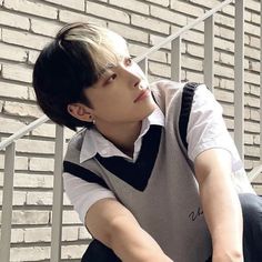 a young man sitting on top of a metal hand rail next to a brick wall