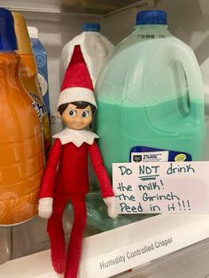 an elf is sitting on top of a shelf next to bottled water and orange juice