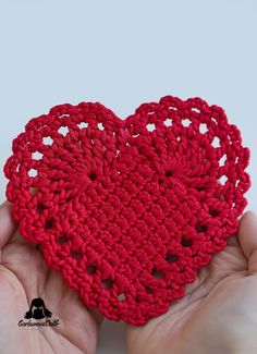 a crocheted heart in the palm of someone's hand