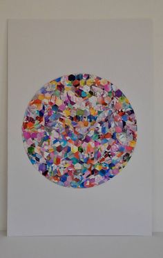 a circular artwork with multicolored confetti on white paper