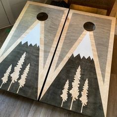 two cornhole boards with trees painted on them sitting on the floor in front of a door