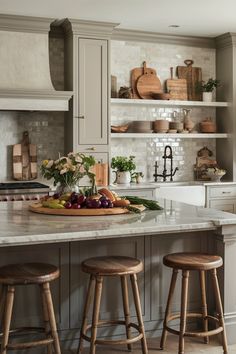 a kitchen with two stools at the center of the island and an open shelving unit behind it