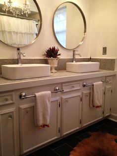 a bathroom with two sinks and mirrors on the wall next to a rug in front of it