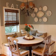 a dining room table and chairs with plates on the wall