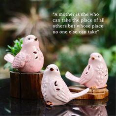 two pink ceramic birds sitting on top of a wooden stump with a quote above them