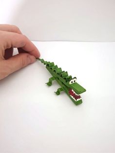 a hand is holding an object that looks like a crocodile