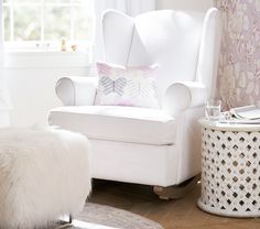 a white chair sitting in a living room next to a window